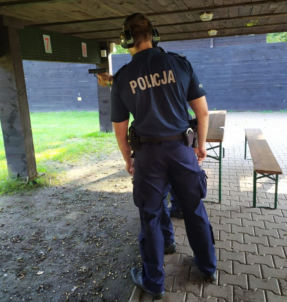 Na zdjęciu policjant nadzorujący strzelanie oraz stróż prawa biorący udział w doskonaleniu zawodowym. 