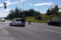 Fotografia kolorowa. Na zdjęciu widoczny policjant ruchu drogowego kierujący ruchem.