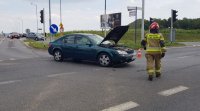 Fotografia kolorowa. Na zdjęciu widoczny ford stojący na skrzyżowaniu.