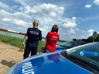 Fotografia kolorowa. Na zdjęciu policjantka oraz ratowniczka wopr-u podczas obserwacji zbiornika