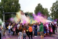 Fotografia kolorowa. Na zdjęciu uczestnicy pikniku podczas wyrzutu proszku holy.