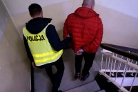 Na zdjęciu policjant prowadzący osobę zatrzymaną