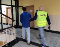 Na zdjęciu osoba zatrzymana prowadzona przez policjanta