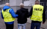 Na zdjęciu policjanci prowadzący zatrzymanego