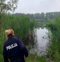 Na zdjęciu umundurowana policjantka obserwująca zbiornik wodny.