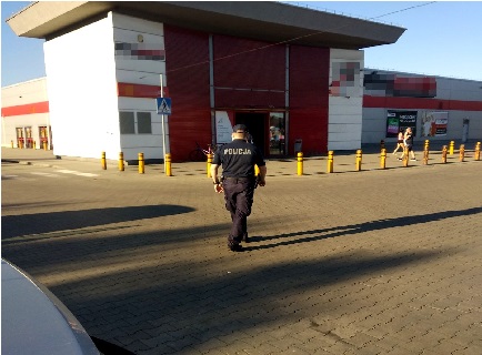 Policjant w mundurze zmierzający do sklepu podczas działań.