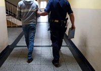 Na zdjęciu umundurowany policjant prowadzący osobę zatrzymaną.