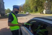 Policjant wręczający odblask kierującemu