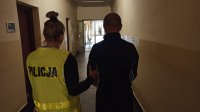 NA zdjęciu policjant prowadzący osobę zatrzymaną