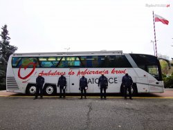 Stojący umundurowani policjanci na tle ambulansu Regionalnego Centrum Krwiodawstwa i Krwiolecznictwa.