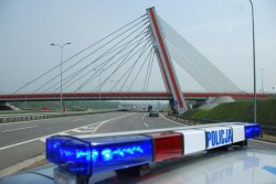 Dach radiowozu na którym umieszczone sygnały świetlne z napisem &quot;POLICJA&quot; na tle autostrady