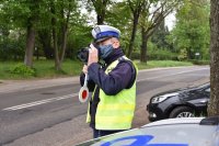 Umundurowany policjant ruchu drogowego kontrolujący prędkość pojazdów przy pomocy urządzenia Trucam.