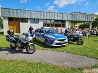 Oznakowany radiowóz, motocykle oraz umundurowani policjanci podczas spotkania z przedszkolakami