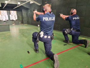 Umundurowani policjanci w postaci klęczącej podczas treningu strzeleckiego.