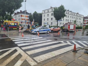 Miejsce zdarzenia drogowego.  W tle pojazdy osobowe uczestniczące w zdarzeniu oraz pojazdy Policji, Straży Pożarnej oraz Pogotowia Ratunkowego