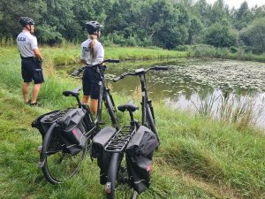 Patrol policyjny pełniący służbę na rowerach, kontrolujący zbiornik wodny