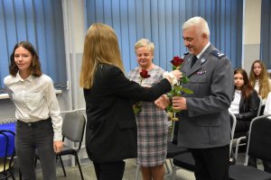 Uczennice wręczają czerwone róże Komendantowi Miejskiemu Policji w Piekarach Śląskich oraz Rzecznik Prasowej Urzędu Celno-Skarbowemu w Katowicach