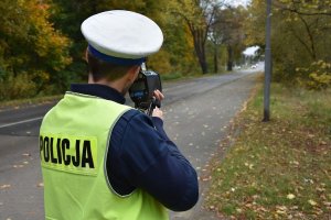 Umundurowany policjant stojący na poboczu podczas kontroli prędkości pojazdów