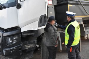 Umundurowany policjant ruchu drogowego stojący obok pojazdu i przeprowadzający badanie kierującego na zawartość alkoholu w wydychanym powietrzu