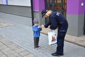 Umundurowana policjantka wręczająca dziecku opaskę w ramach prowadzonej przez Śląską Policję kampanii &quot;Mamo! Tato! tutaj jestem&quot;