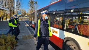 Umundurowani policjanci stoją obok autobusu komunikacji miejskiej