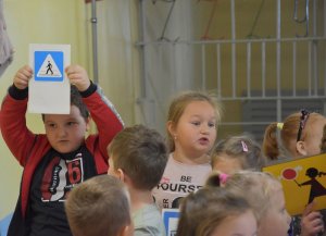 Dzieci trzymające w rękach wydrukowane znaki drogowe.