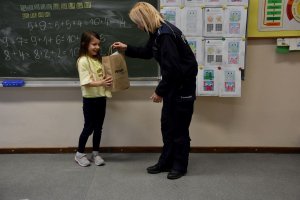 Umundurowana policjantka wręczająca nagrodę laureatom konkursu.