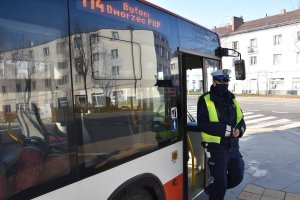 Umundurowany policjant wychodzi z autobusu komunikacji miejskiej