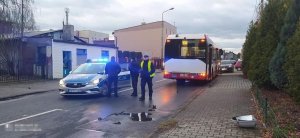 Oznakowany policyjny radiowóz zabezpieczający miejsce zdarzenia drogowego, w tle autobus komunikacji miejskiej