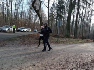 Uczestnicy biegu na trasie. W tle pojazdy oraz policyjny radiowóz