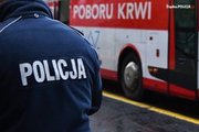 Umundurowany policjant na tle ambulansu do poboru krwi