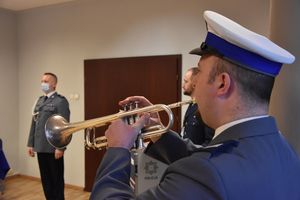 Policyjny trębacz. W tle policjanci w umundurowaniu galowym