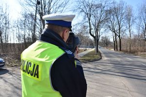 Umundurowany policjant w kamizelce odblaskowej podczas kontroli prędkości pojazdów