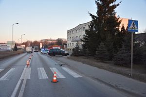 Droga, przejście dla pieszych, ustawione słupki oddzielające pasy ruchu. W oddali stoją pojazdy uprzywilejowane