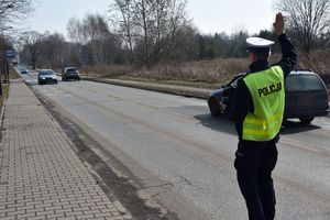 Umundurowany policjant daje sygnał do zatrzymania kierującemu pojazdem