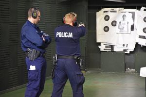 Dwaj policjanci podczas szkolenia strzeleckiego na strzelnicy. W tle tarcze strzeleckie