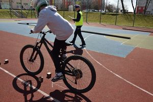 Uczeń jedzie na rowerze. Obok idzie umundurowany policjant ruchu drogowego