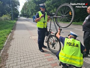 Umundurowani policjanci ruchu drogowego kontrolują rowerzystę oraz sprawdzają jednoślad