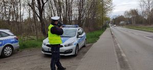 Umundurowany policjant kontroluje prędkość pojazdów w rejonie przejść dla pieszych