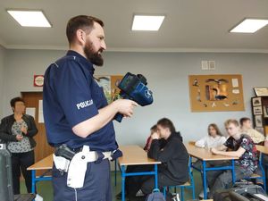 Policjant prezentujący uczniom laserowy miernik prędkości