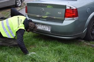 Policyjny technik podczas wykonywania czynności przy samochodzie