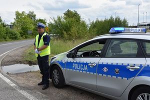 Policjant ruchu drogowego stoi przy radiowozie