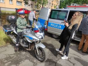 Dziewczynka siedzi na policyjnym motocyklu. Obok policyjny furgon