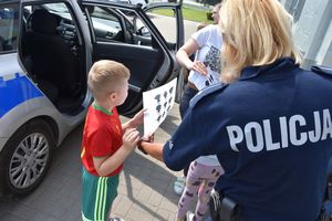 Policjantka wręcza kolorowankę dziecku