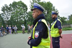 Policjanci ruchu drogowego podczas egzaminy na kartę rowerową. W tle uczniowie z rowerami.