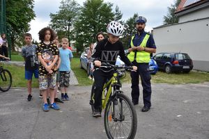 Uczeń jadący na rowerze. Obok stoi policjant