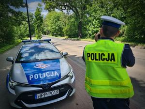 Umundurowany policjant stoi obok radiowozu