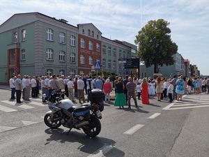 Policyjny motocykl podczas zabezpieczenia procesji. W tle idący ludzie.