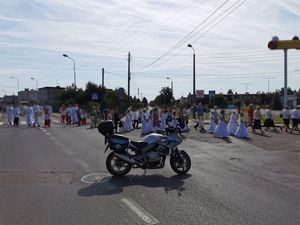 Policyjny motocykl podczas zabezpieczenia procesji. W tle idący ludzie.