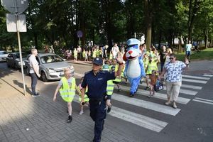 Policjantka wraz z dziećmi przechodzi przez oznakowane przejście dla pieszych